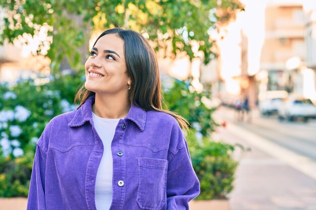 Young hispanic woman smiling happy walking at the park