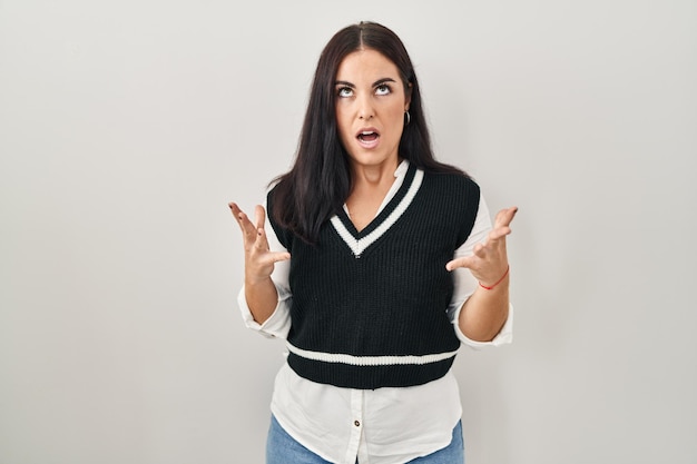 Free photo young hispanic woman standing over isolated background crazy and mad shouting and yelling with aggressive expression and arms raised frustration concept