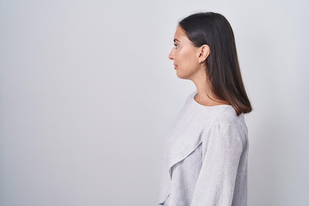 Young hispanic woman standing over white background looking to side relax profile pose with natural face and confident smile