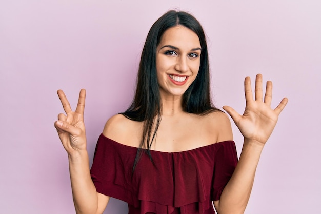 Free photo young hispanic woman wearing casual clothes showing and pointing up with fingers number seven while smiling confident and happy