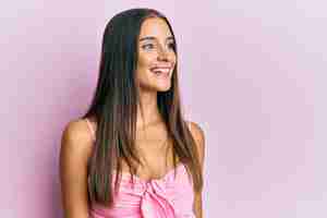 Free photo young hispanic woman wearing casual style with sleeveless shirt looking away to side with smile on face, natural expression. laughing confident.