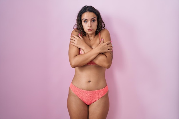 Free photo young hispanic woman wearing lingerie over pink background shaking and freezing for winter cold with sad and shock expression on face