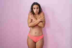 Free photo young hispanic woman wearing lingerie over pink background shaking and freezing for winter cold with sad and shock expression on face