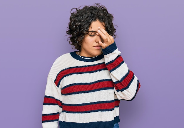 Giovane donna ispanica con i capelli ricci che indossa abiti casual stanco strofinando il naso e gli occhi sentendo affaticamento e mal di testa concetto di stress e frustrazione