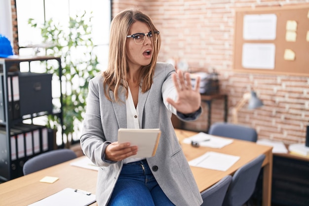 Free photo young hispanic woman working at the office wearing glasses doing stop gesture with hands palms, angry and frustration expression