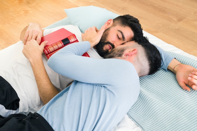 Young homosexual couple lying on bed kissing