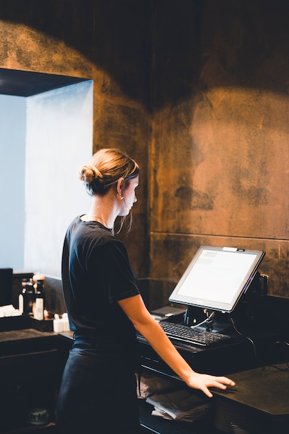 Young hostess standing near cash register
