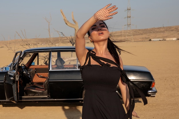 젊은 뜨거운 모델은 사막에 서서 그녀의 손으로 태양을 닫습니다. 고품질 사진