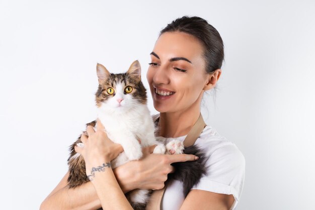 A young housewife in an apron on a white background holds her beloved pet a big fluffy cat a happy family