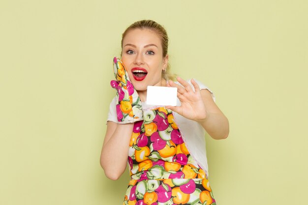 young housewife in shirt and colored cape holding white card on green