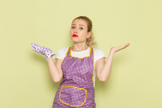 young housewife in shirt and colored cape posing with confused face on green