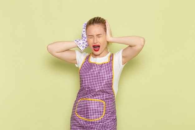 Free photo young housewife in shirt and purple cape covering her ears on green