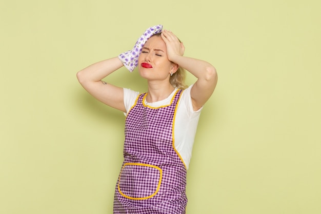 Free photo young housewife in shirt and purple cape depressed on green