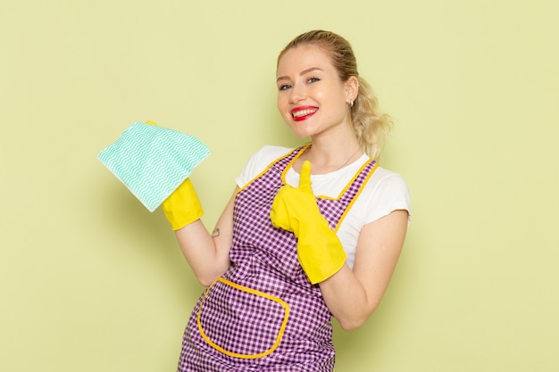 young housewife in shirt and purple cape with yellow gloves holding green rag on green