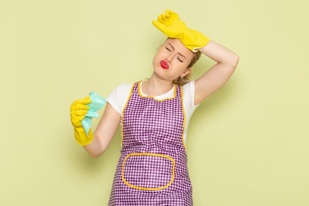 young housewife in shirt and purple cape with yellow gloves holding green