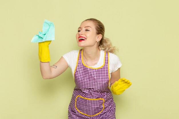 young housewife in shirt and purple cape yellow gloves smiling on green