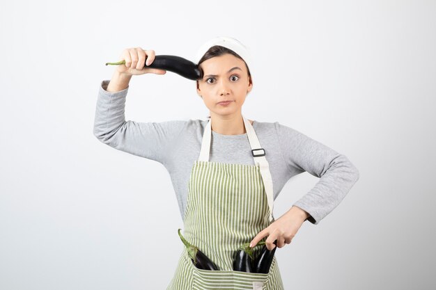 Young housewife showing single eggplant on white 