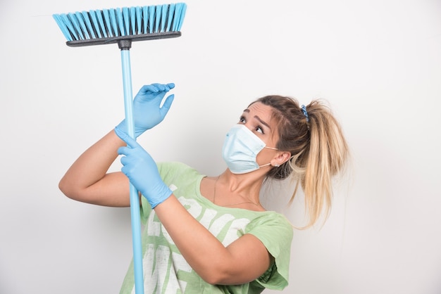 Young housewife with facemask looking at broom.