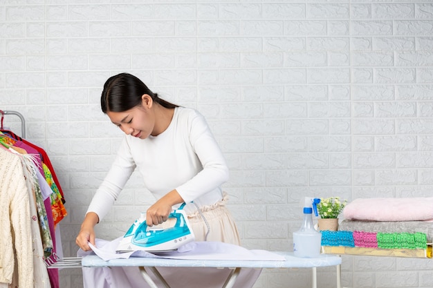 Free photo young housewives who are using irons ironing his clothes on a white brick .