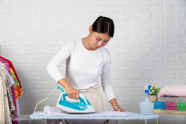 Free photo young housewives who are using irons ironing his clothes on a white brick .