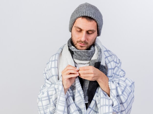 Young ill man wearing winter hat and scarf wrapped in plaid opening plaster isolated on white