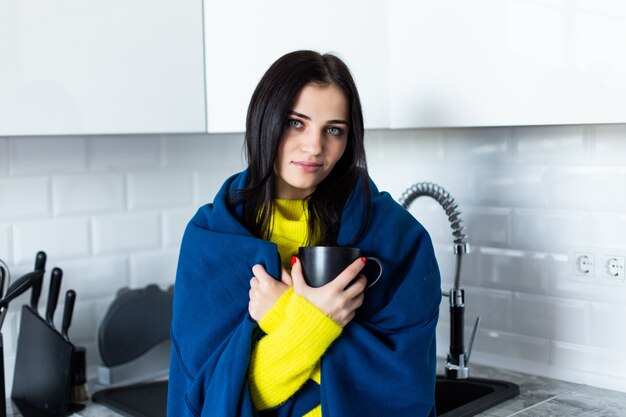 Young ill woman drink tea feel sick at kitchen