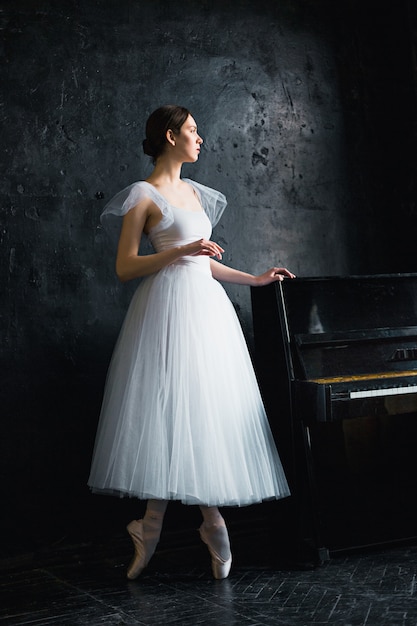 Young and incredibly beautiful ballerina is posing in a black studio