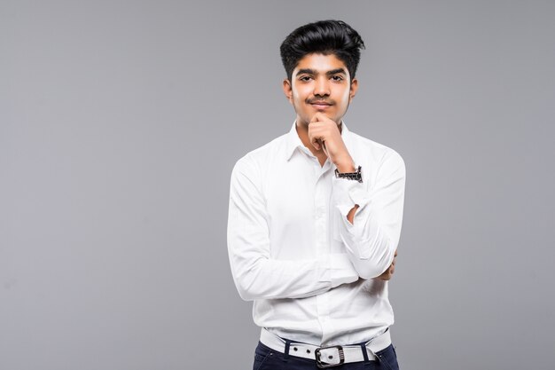 Young Indian businessman wearing white shirt and tie against gray wall