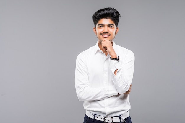 Young Indian businessman wearing white shirt and tie against gray wall