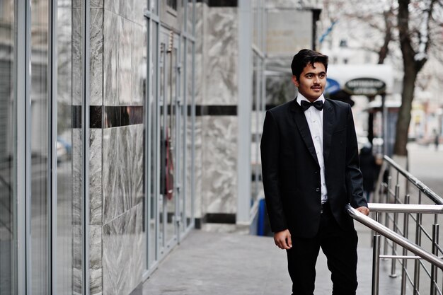 Young indian man on black suit and bow tie posed outdoor