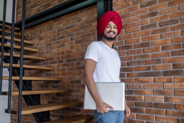 Young indian man in red turban standing on stairs