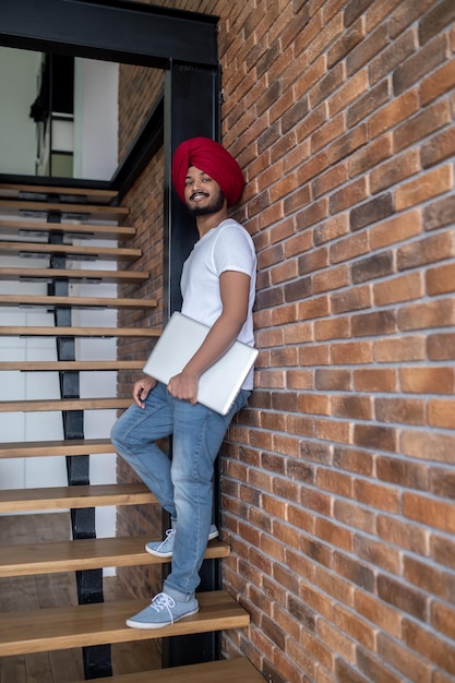 Free photo young indian man in red turban standing on stairs