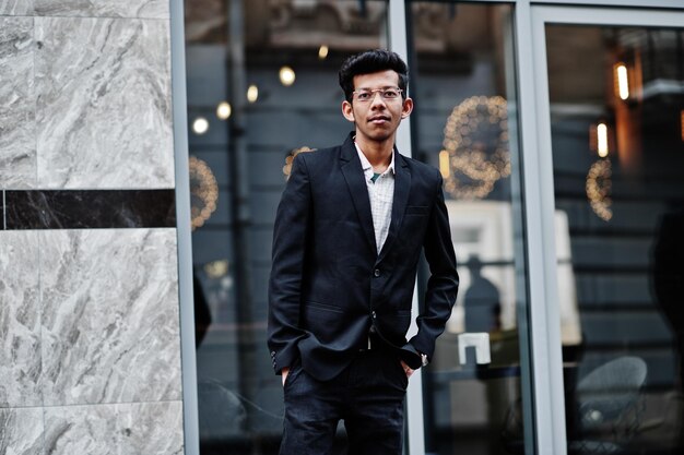 Young indian man on suit and glasses posed outdoor