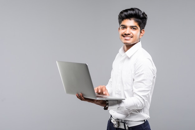 회색 벽에 노트북으로 젊은 인도 사람