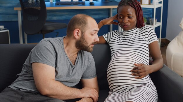 Young interracial parents sitting together on couch