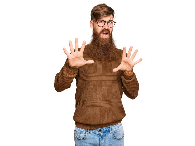 Free photo young irish redhead man wearing casual clothes and glasses afraid and terrified with fear expression stop gesture with hands, shouting in shock. panic concept.