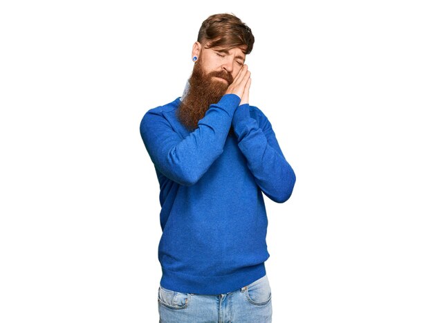 Young irish redhead man wearing casual clothes sleeping tired dreaming and posing with hands together while smiling with closed eyes.