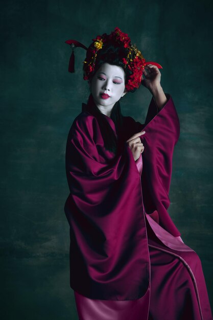 Young japanese woman as geisha on dark green. Retro style, comparison of eras concept