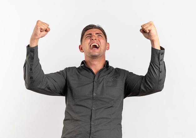 Young joyful blonde handsome man raises fists up looking up isolated on white background with copy space