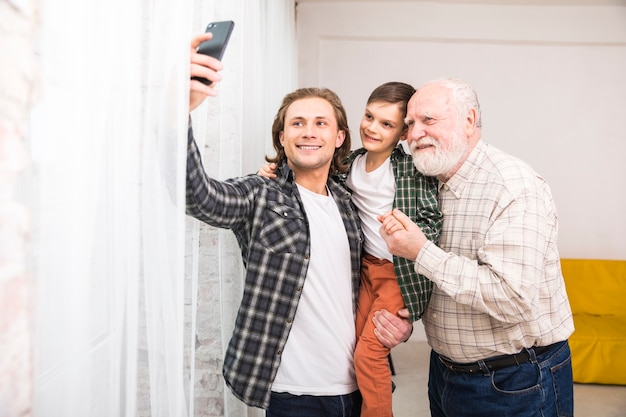 Free photo young joyful man taking selfie with family