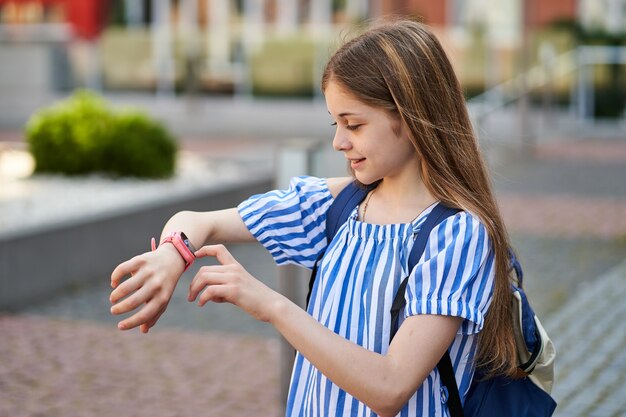 어린 소녀는 분홍색 smartwatch.near 학교로 부모님과 영상 통화를 합니다.