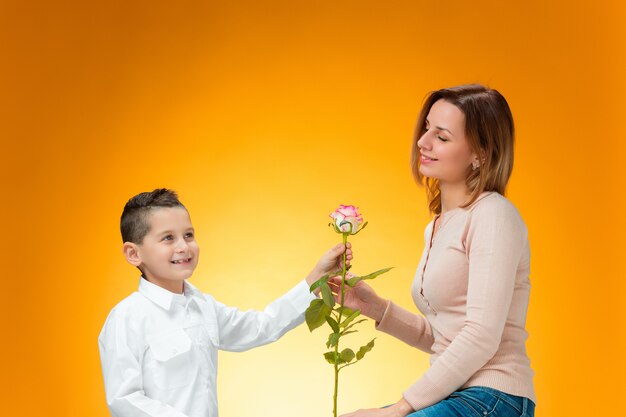 Young kid giving red rose to his mom