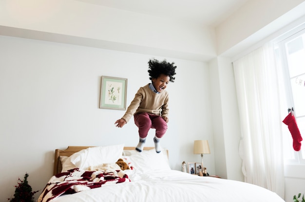 ベッドの上でジャンプして楽しい時間を過ごしている幼い子供