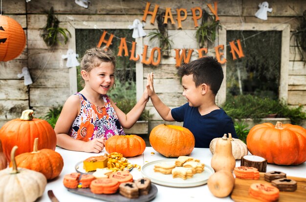 Young kids carving Halloween jack-o-lanterns