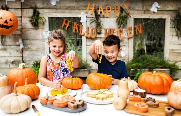 Young kids carving Halloween jack-o-lanterns