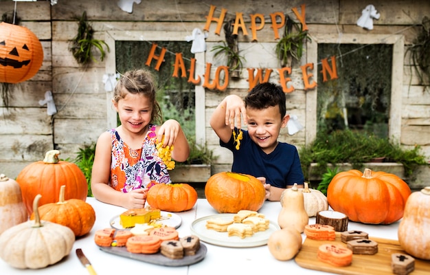 Young kids carving Halloween jack-o-lanterns