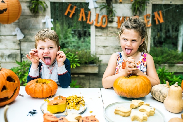 Young kids carving Halloween jack-o-lanterns