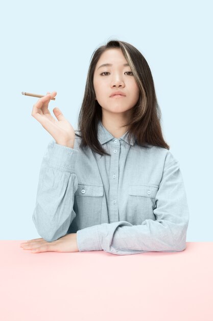 Молодые корейские женщины курят сигару, сидя за столом в студии.