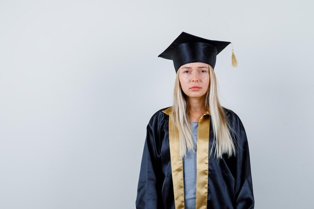 Young lady in academic dress looking at camera and looking wistful