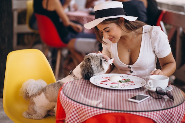 Young lady in bar with cute dog having lunch